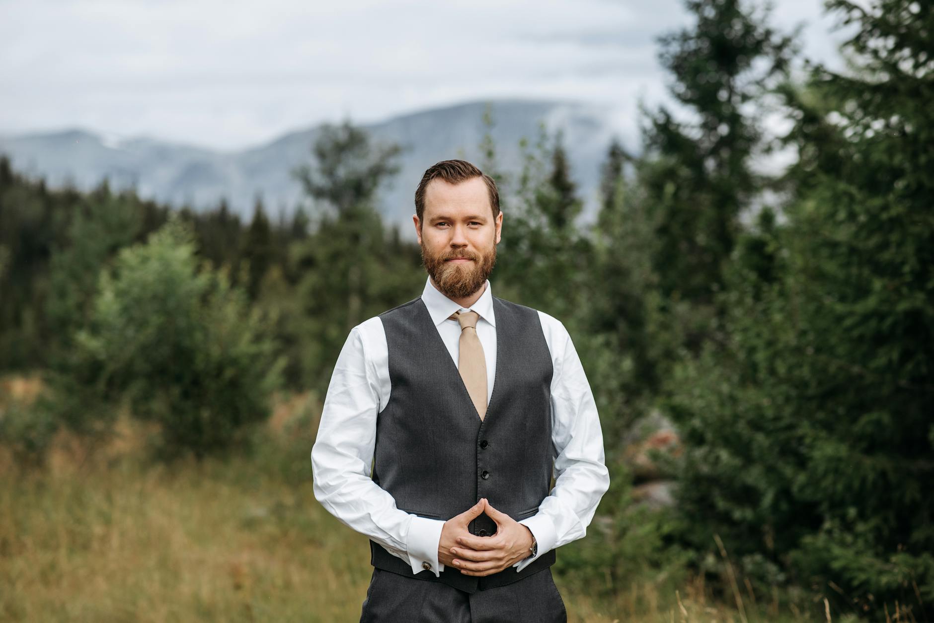 a bearded man in gray vest smiling at the camera